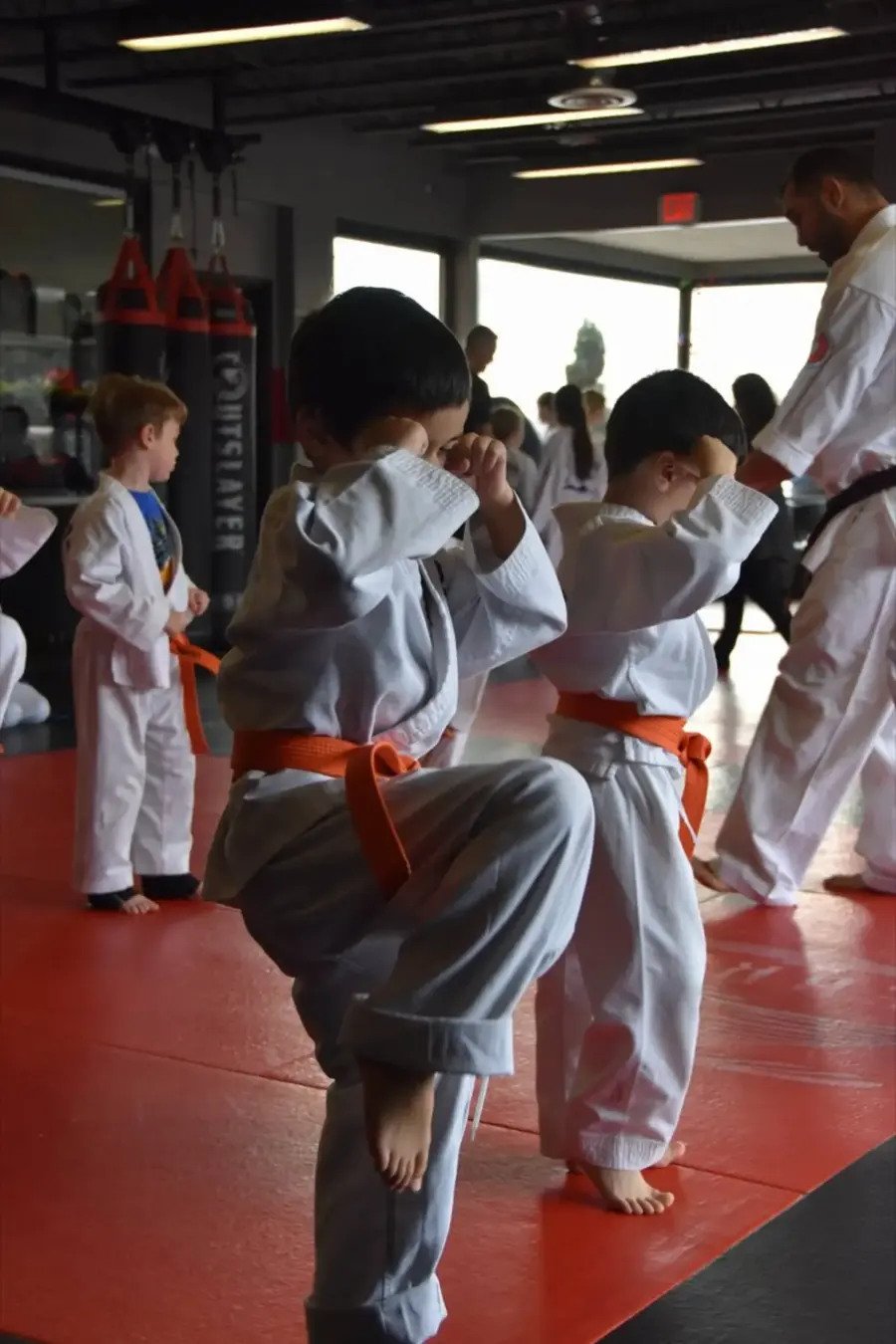 Children in uniform practicing a stance together on the mats